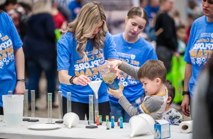 A woman helps a boy with a science experiment.